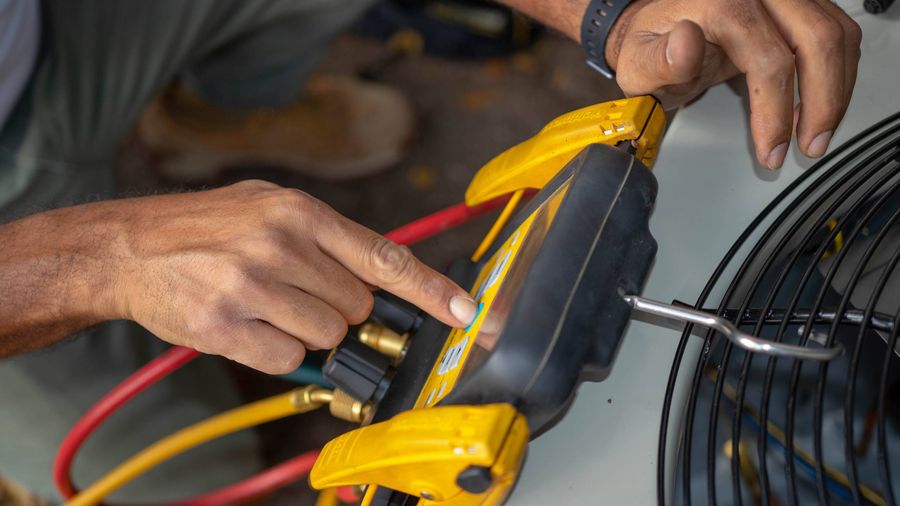 Technician using refrigerant gauges to diagnose an AC condenser unit