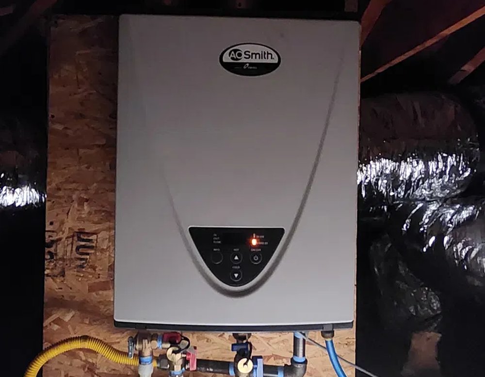Tankless water heater installed in an attic, connected to gas and water lines